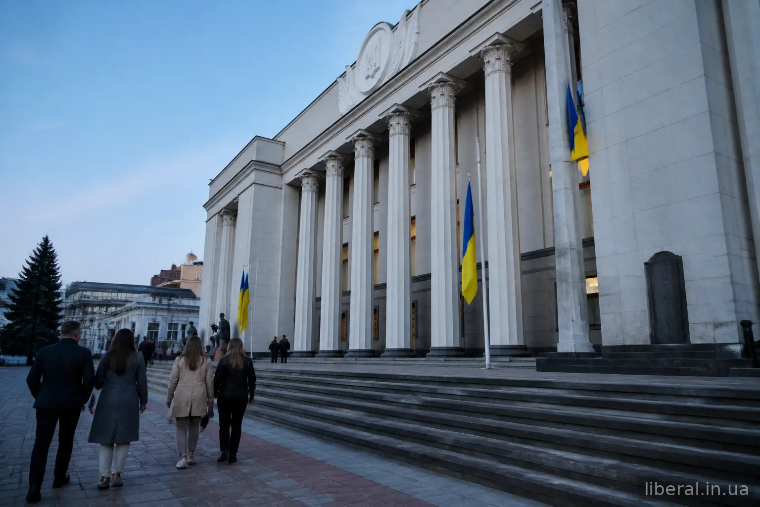 Будівля парламенту з прапорами та людьми біля входу