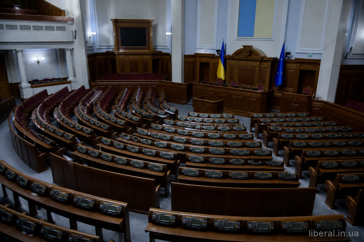 Порожня сесійна зала парламенту з трибуною та прапорами України